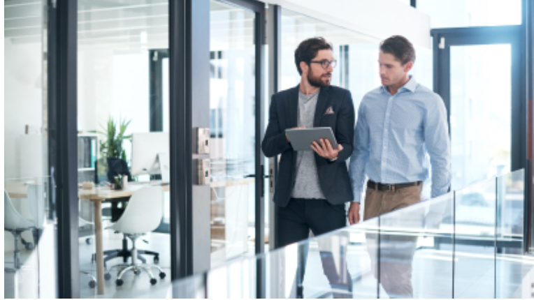 two individuals walking in an office setting